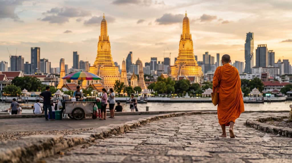 Golden Bangkok temple at sunset with monk walking budget travel